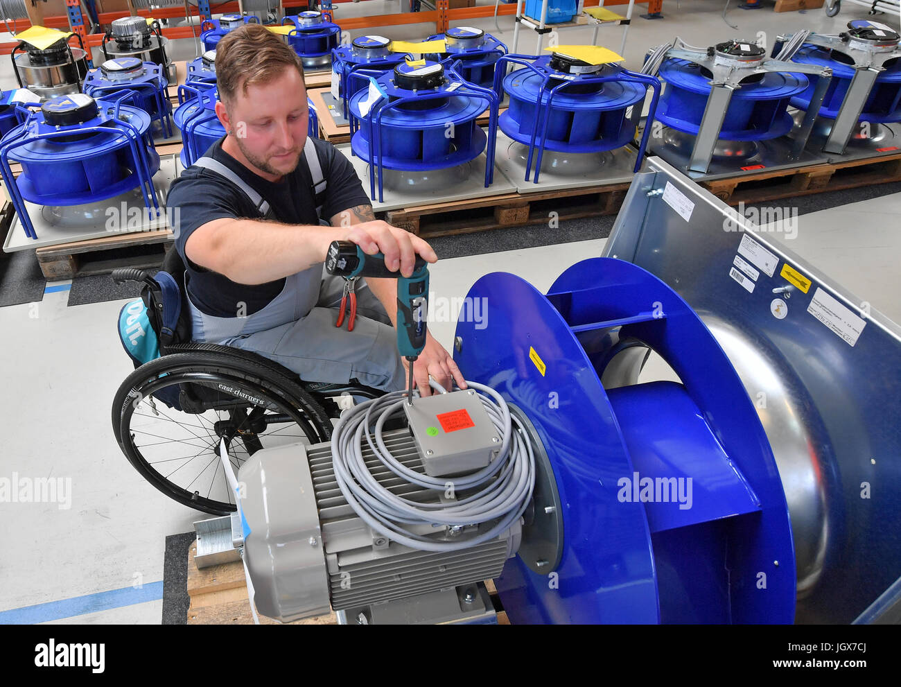 Mitarbeiter Daniel bei der Arbeit in einem Arbeitsbereich für Motorklemmen an DencoHappel Production GmbH in Wurzen, Deutschland, 11. Juli 2017 Schlesinger. Schlesinger benutzt einen Rollstuhl seit einem Autounfall im Jahr 2012. Drei Viertel der ein Jahr nach seinem Unfall zurückgekehrt Schlesinger an den barrierefreien Arbeitsbereich bei der Firma arbeiten. Foto: Hendrik Schmidt/Dpa-Zentralbild/ZB Stockfoto