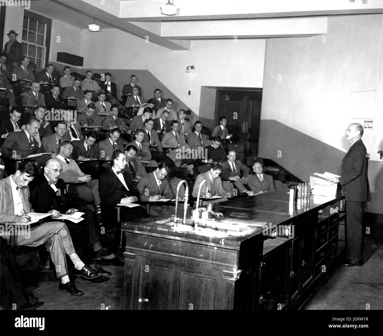 Ein Abendkurs Hochschule Johns-Hopkins-Universität befindet sich in einem Hörsaal Heften Notizen als Professor an der Vorderseite des Raumes einen Vortrag, 1930 steht. Stockfoto