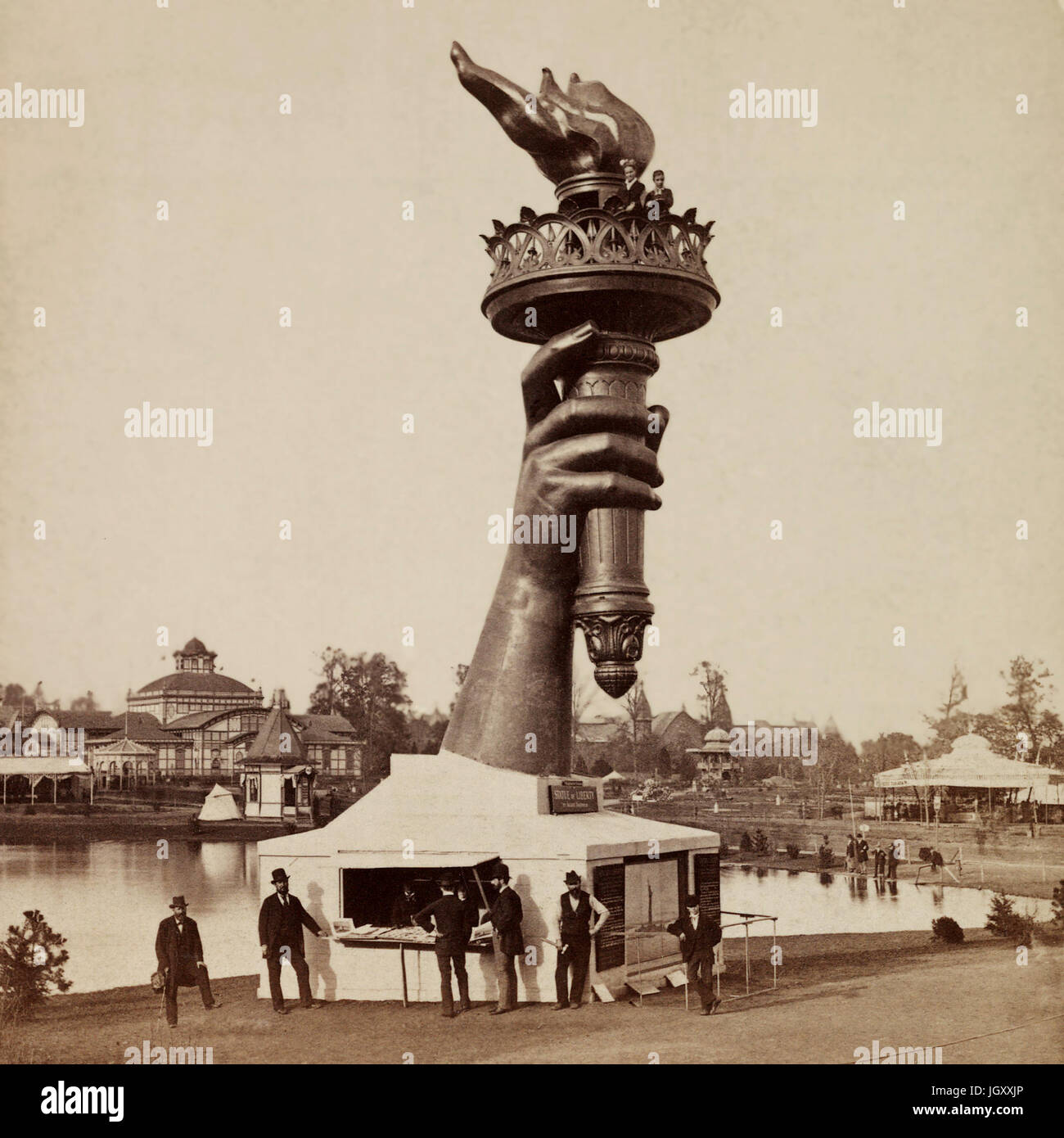 Die Fackel und Bestandteil der Arm der Statue of Liberty, auf dem Display an der 1876 Centennial Exhibition in Philadelphia. Informationsstand auf der Basis von Arm und zwei Personen am Geländer unten Flamme der Fackel zu sehen. Stockfoto