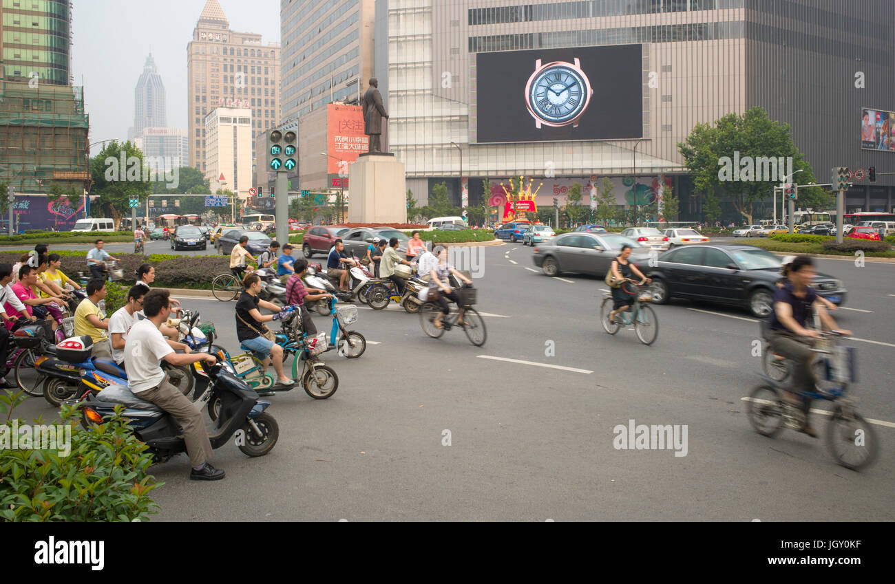 Autos, Fahrräder und Elektroroller verhandeln Xinjiekou in abendlichen Hauptverkehrszeiten. Nanjing, China Stockfoto