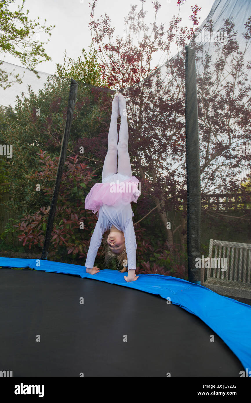 Mädchen auf Trampolin trägt Tutu macht handstand Stockfoto