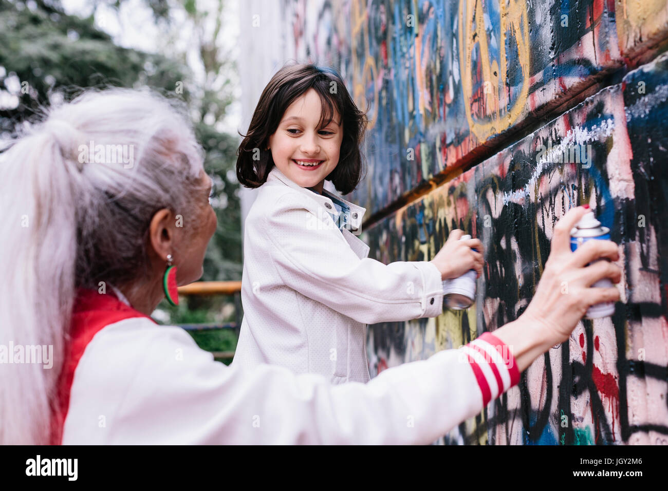 Reife Frau und Mädchen spritzen Malerei Graffitiwand zusammen Stockfoto