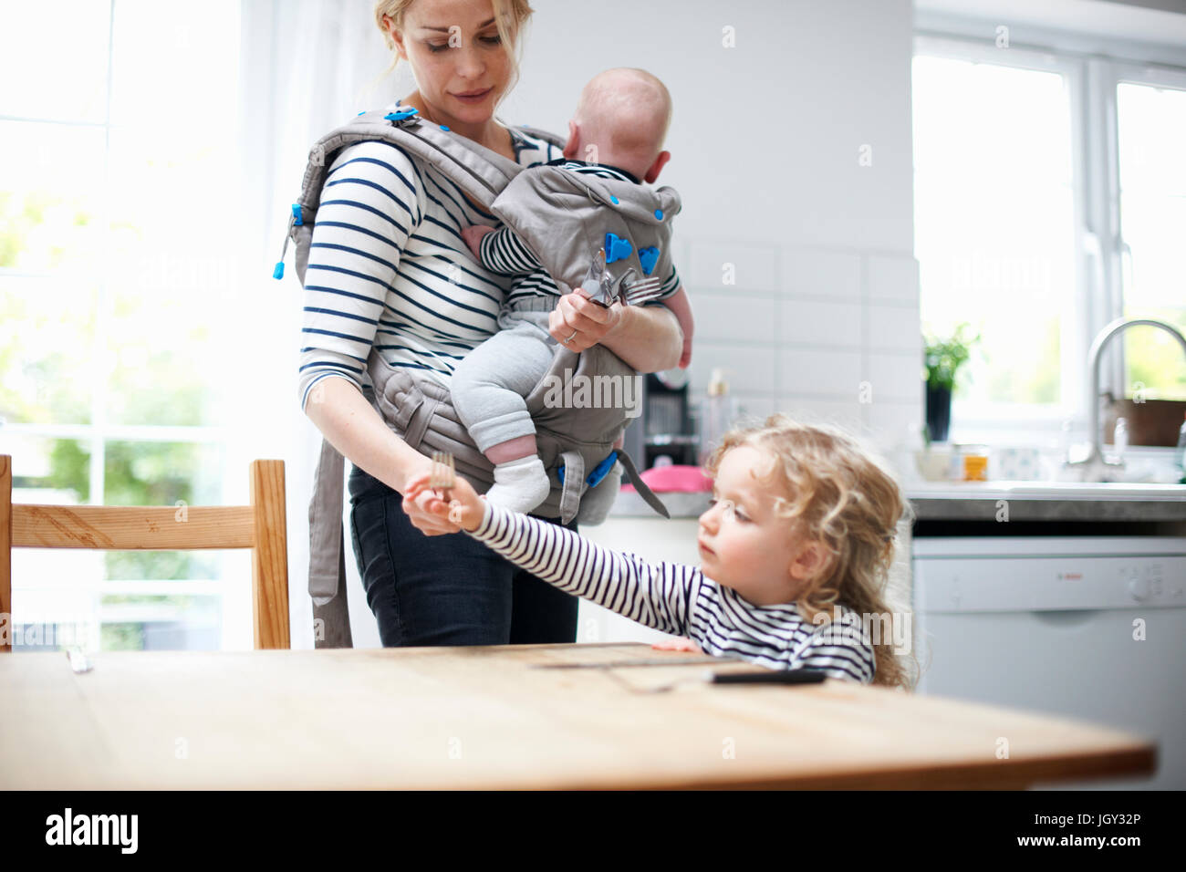 Junges Mädchen helfen Laien Tabelle Mutter, Mutter mit jungen in Schlinge Stockfoto