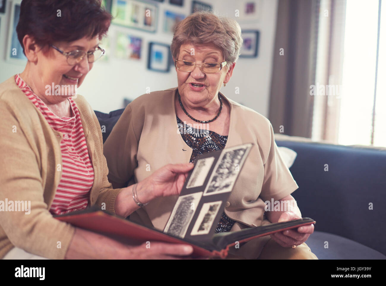 Zwei Frauen in Führungspositionen auf Sofa, Blick auf alten Fotoalbum Stockfoto