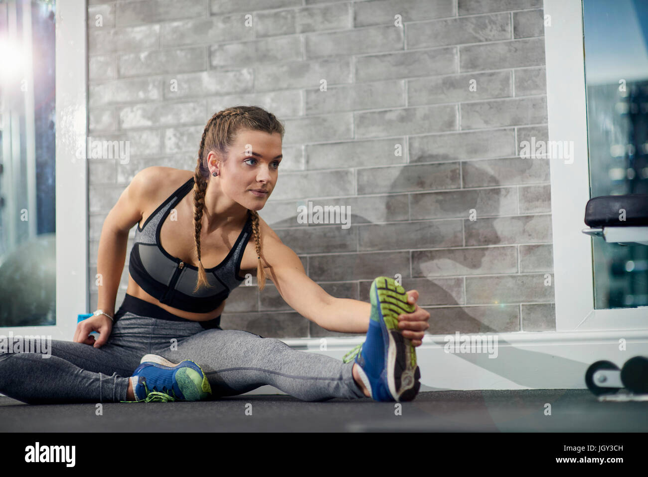 Junge Frau Ausbildung, rührende Zehen im Fitness-Studio Stockfoto