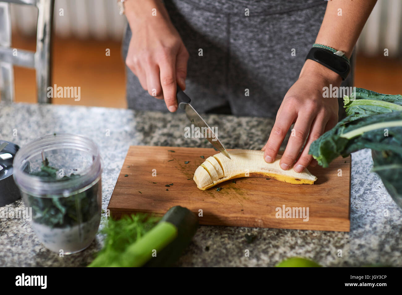 Hände der jungen Frau, die Banane am Küchentisch schneiden Stockfoto