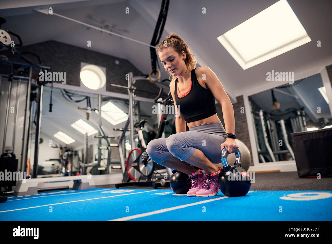 Junge Frau, training, Vorbereitung, Wasserkocher Glocken im Fitness-Studio zu heben Stockfoto