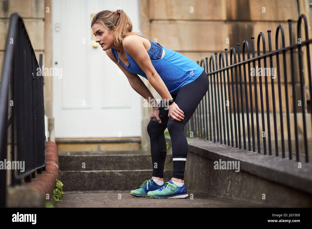 Erschöpfte junge weibliche Läufer vor der Tür Stockfoto