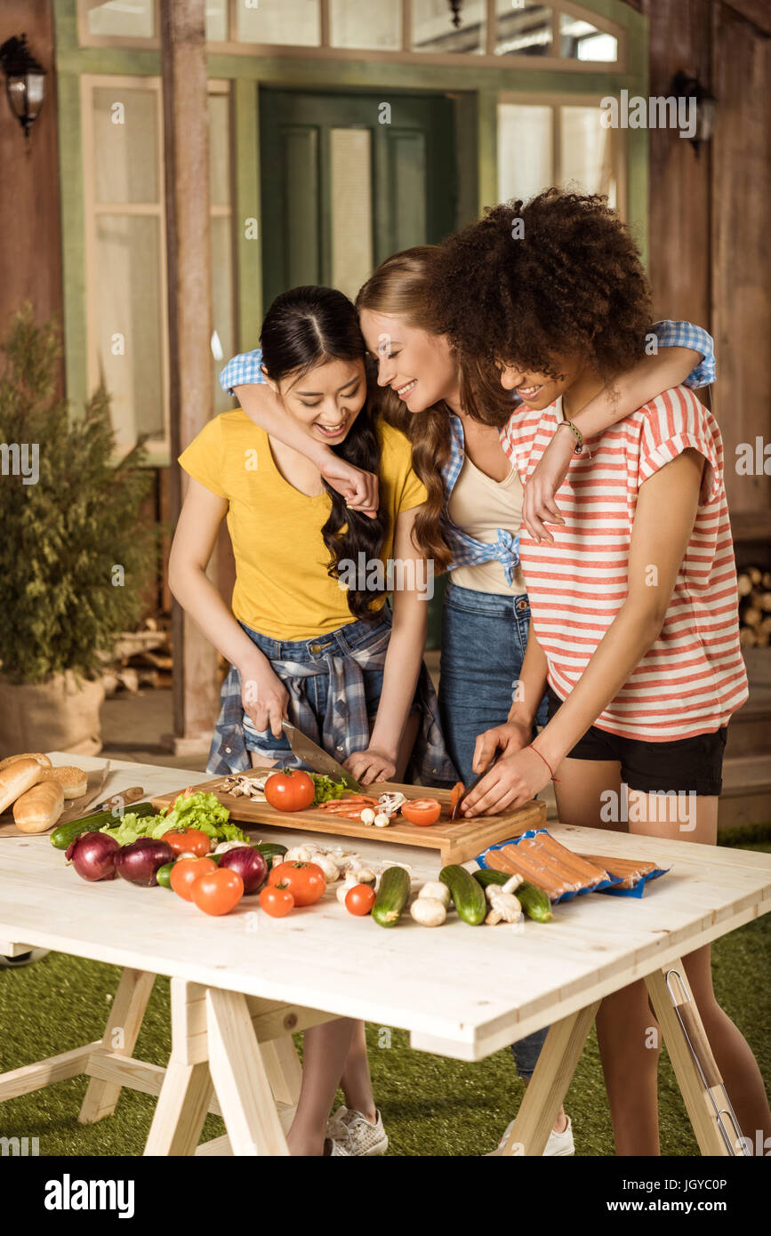 Lächelnde junge Frauen schneiden Sie frisches Gemüse bei Picknick Stockfoto