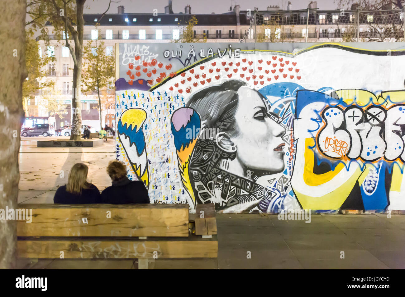 2 Personen auf einer Bank Place de la Republique vor einem Graff. Hommage an die Opfer der Terroranschläge am 13. November. Stockfoto