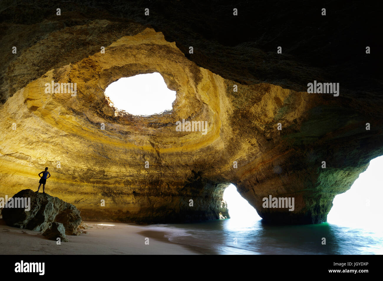 Silhouette einer Frau, die auf den Felsen in Benagil Höhle, ALgarve, Portugal. Stockfoto