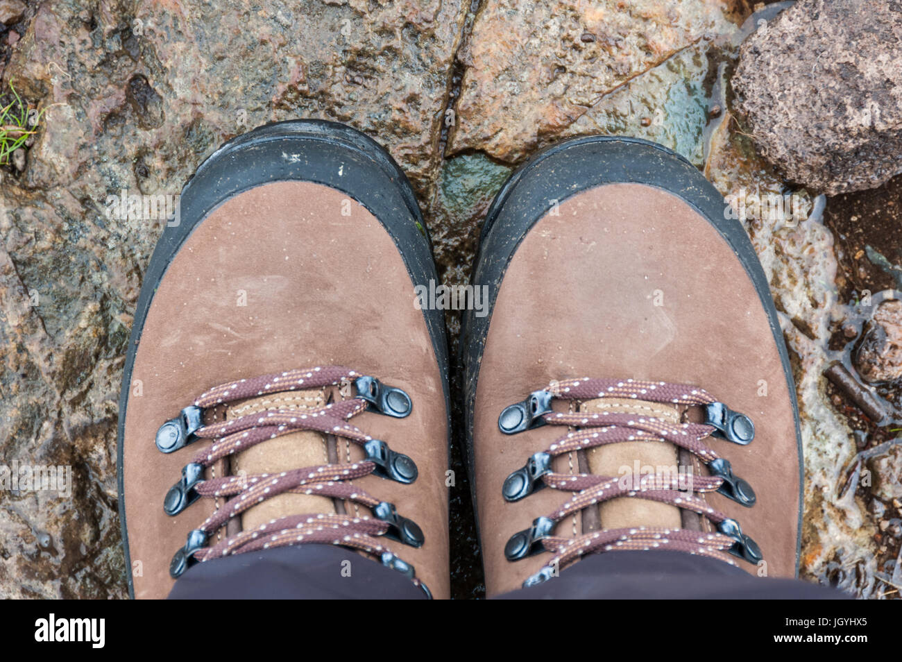 Ein paar braune Wanderstiefel auf nassen Felsen in der Natur. Stockfoto