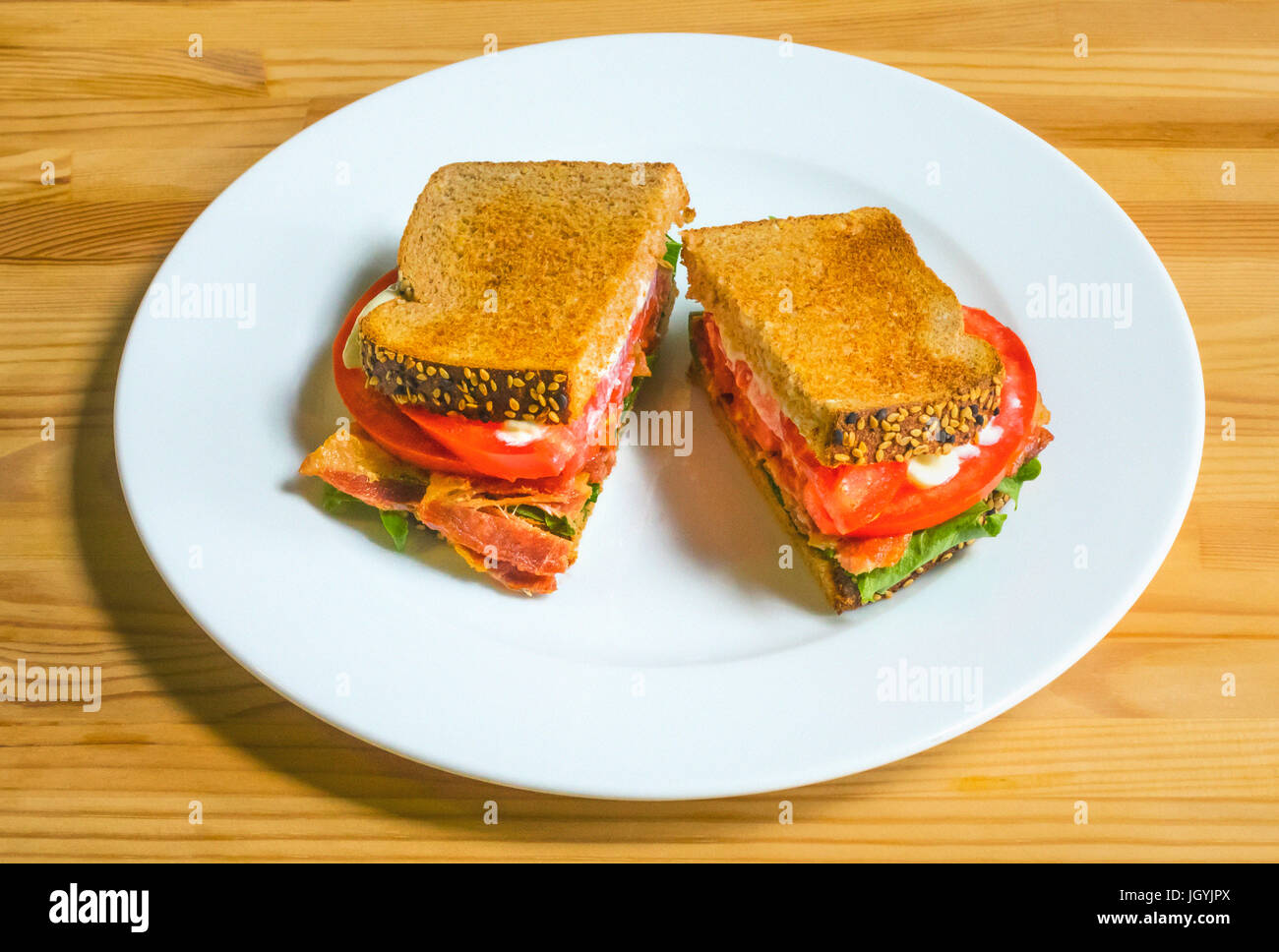 Ein BLT auf einem weißen Teller mit Speck, Salat, Tomate, und Mayonnaise auf geröstetem Brot, einer klassischen American sandwich Stockfoto