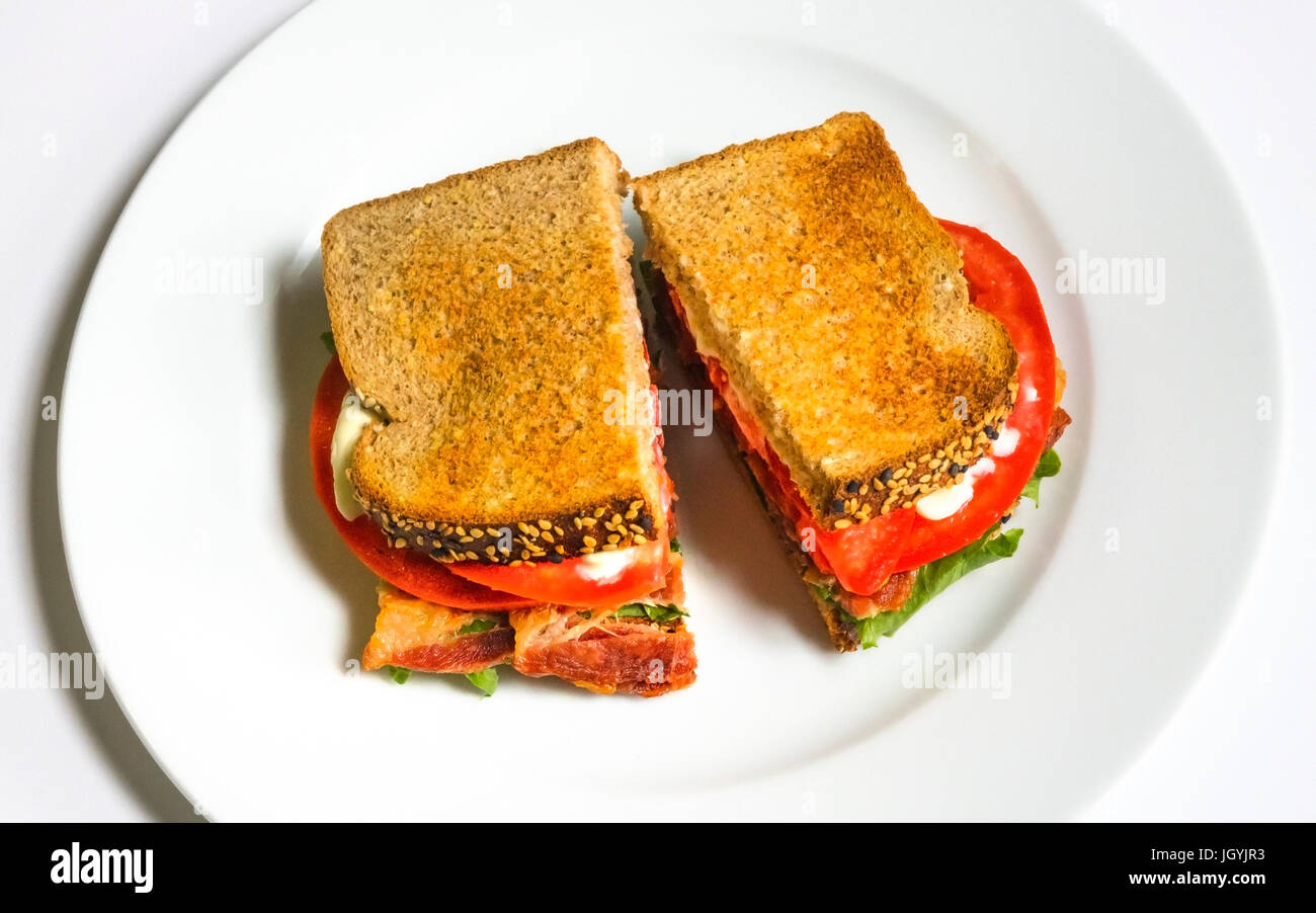 Ein BLT auf einem weißen Teller mit Speck, Salat, Tomate, und Mayonnaise auf geröstetem Brot, einer klassischen American sandwich Stockfoto