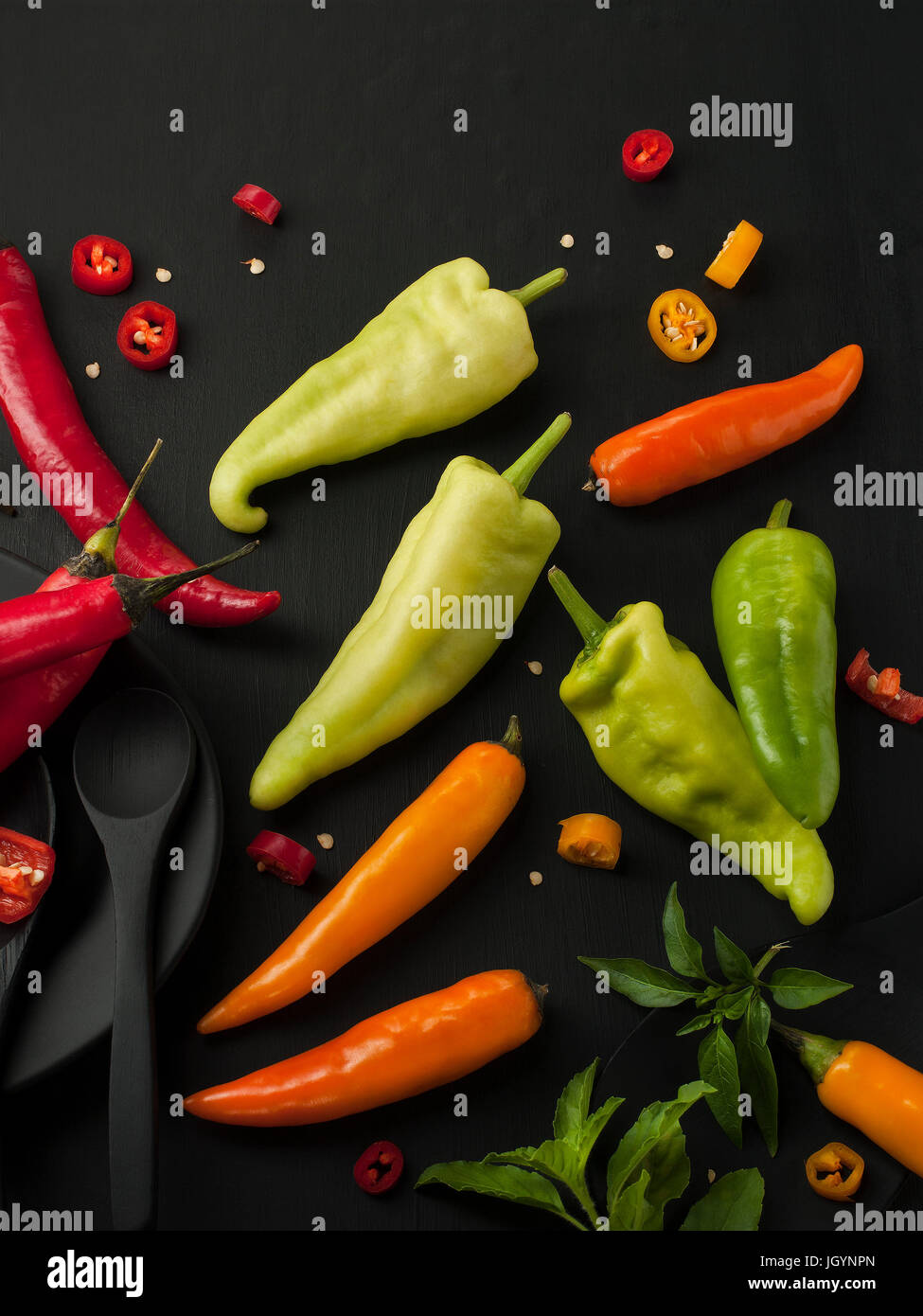Kunst Stillleben von red hot Chili peppers Paprika würzen Mixer Essen Kraut oder gesunde Ernährung auf schwarzem Geschirr auf schwarzem Hintergrund aus Holz Stockfoto
