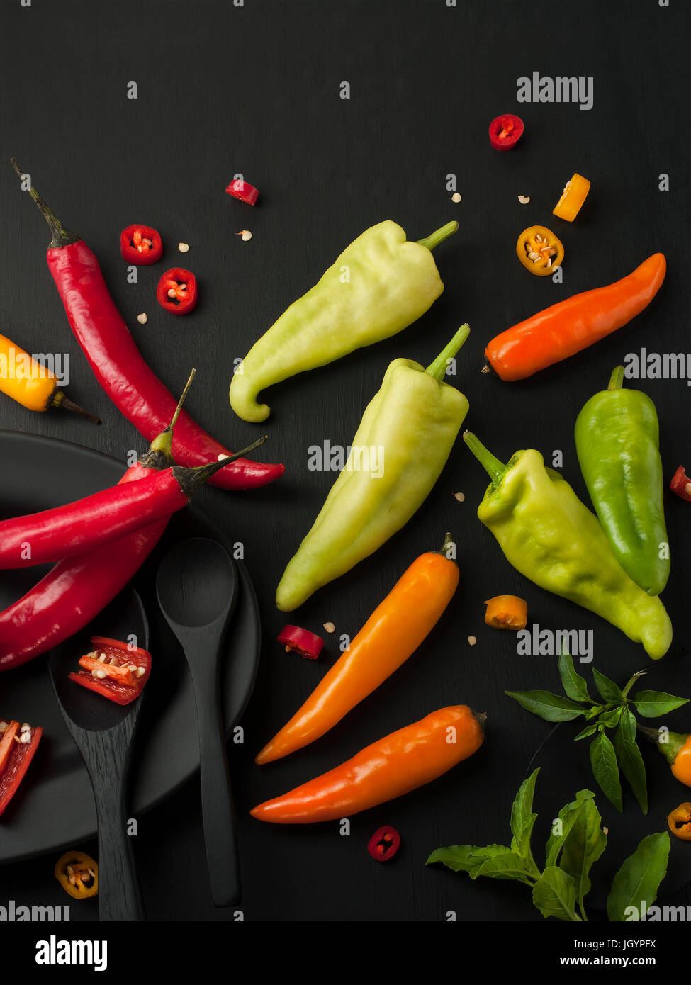 Kunst Stillleben von red hot Chili peppers Paprika würzen Mixer Essen Kraut oder gesunde Ernährung auf schwarzem Geschirr auf schwarzem Hintergrund aus Holz Stockfoto