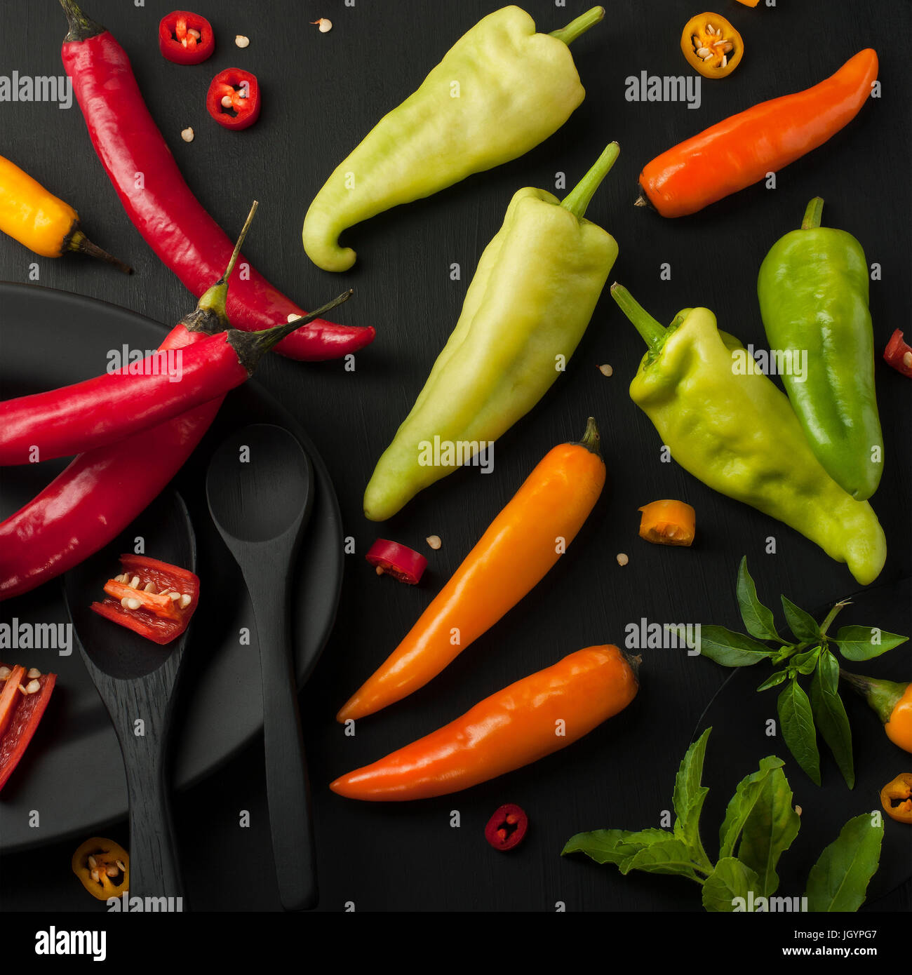 Kunst Stillleben von red hot Chili peppers Paprika würzen Mixer Essen Kraut oder gesunde Ernährung auf schwarzem Geschirr auf schwarzem Hintergrund aus Holz Stockfoto
