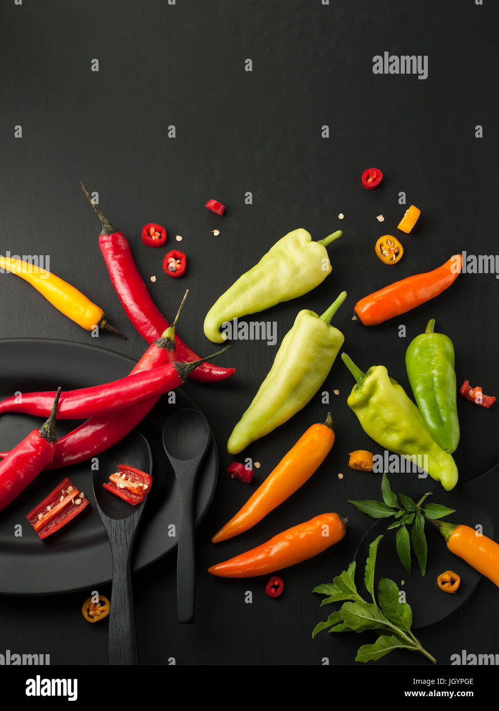 Kunst Stillleben von red hot Chili peppers Paprika würzen Mixer Essen Kraut oder gesunde Ernährung auf schwarzem Geschirr auf schwarzem Hintergrund aus Holz Stockfoto