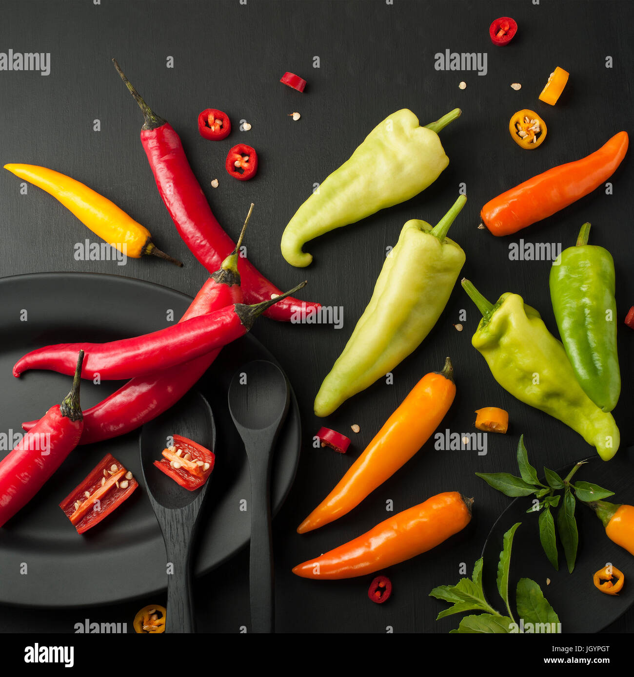 Kunst Stillleben von red hot Chili peppers Paprika würzen Mixer Essen Kraut oder gesunde Ernährung auf schwarzem Geschirr auf schwarzem Hintergrund aus Holz Stockfoto