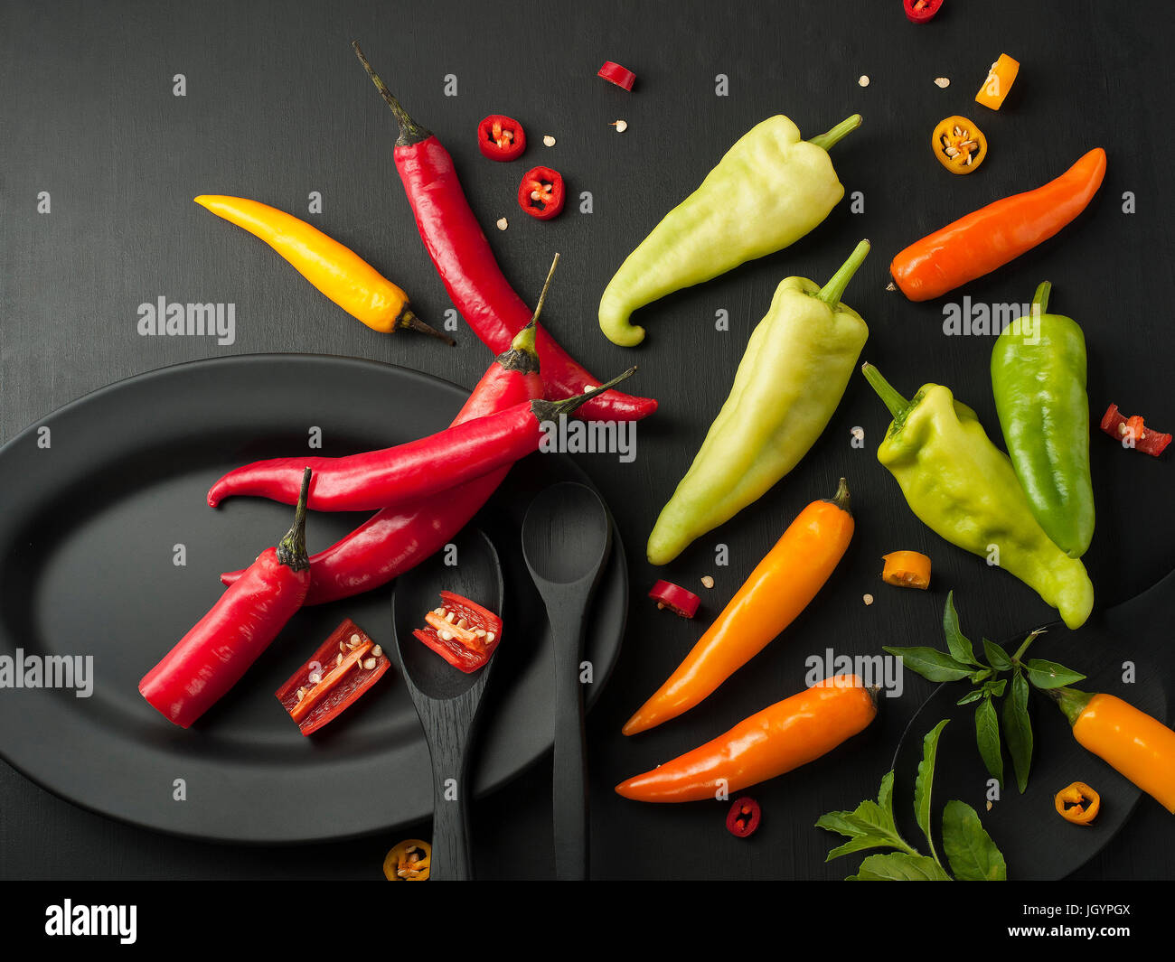 Kunst Stillleben von red hot Chili peppers Paprika würzen Mixer Essen Kraut oder gesunde Ernährung auf schwarzem Geschirr auf schwarzem Hintergrund aus Holz Stockfoto