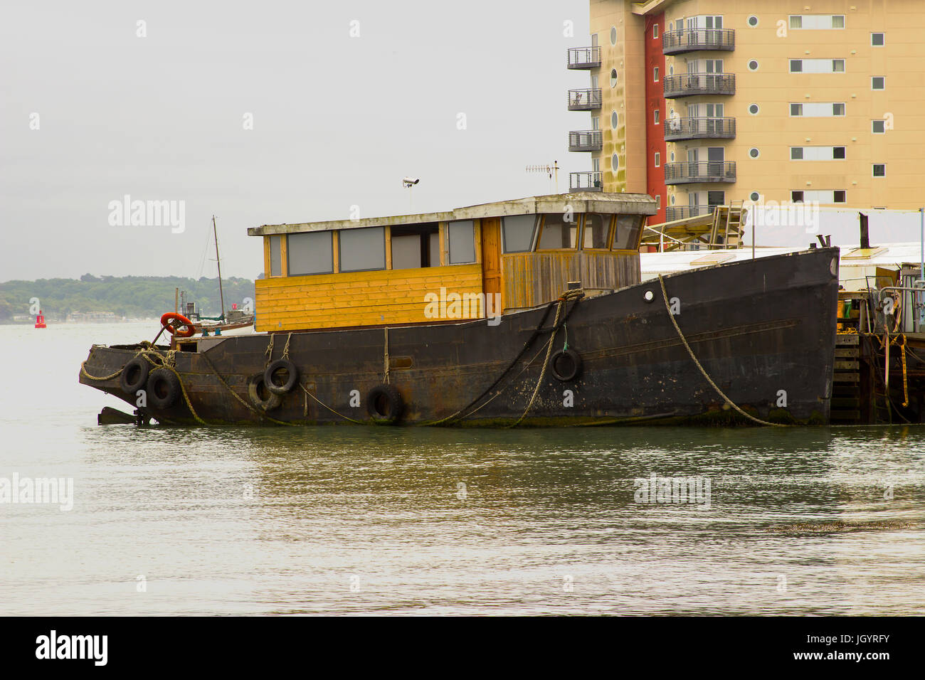 Ein Schlepper in den Prozess der konvertiert ein Sportboot gefesselt am Kai im Hafen von Hythe auf Southampton Water auf der südlichen Küste von En Stockfoto