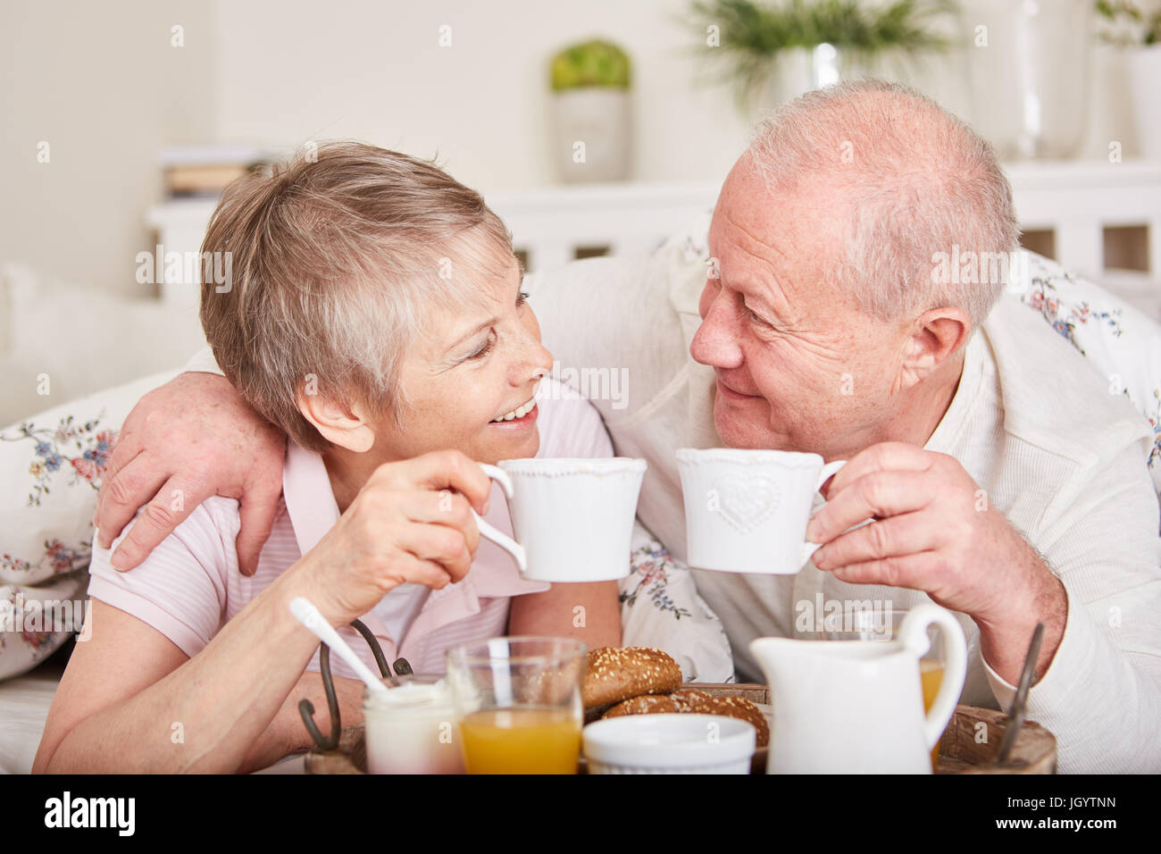 Senioren in der Liebe haben romantisches Frühstück im Bett zusammen Stockfoto