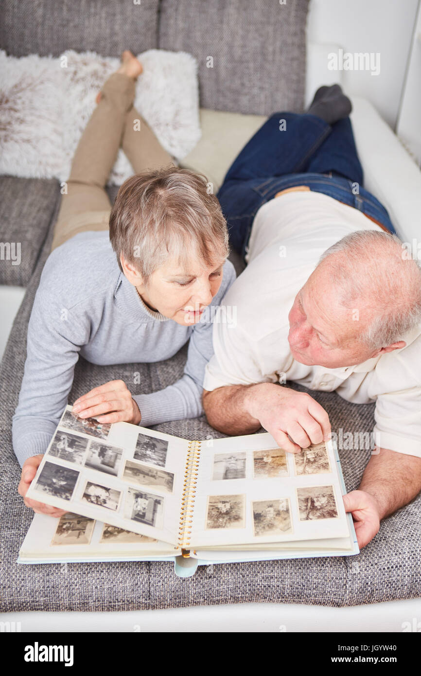 Älteres Paar mit Fotoalbum auf Couch als Erinnerung an schöne Zeiten Stockfoto