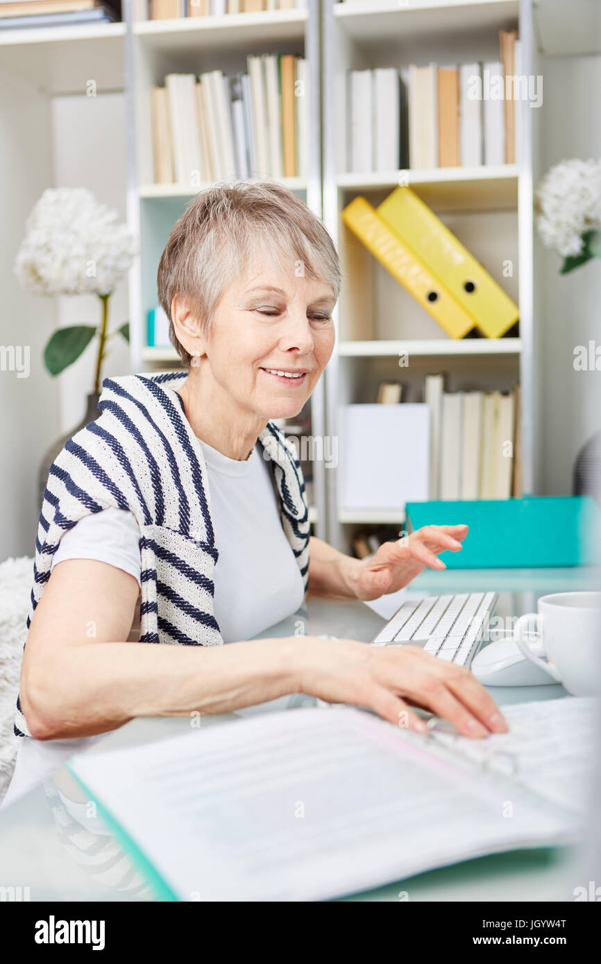 Senior Geschäftsfrau am Arbeitsplatz steuert Office-Dateien Stockfoto