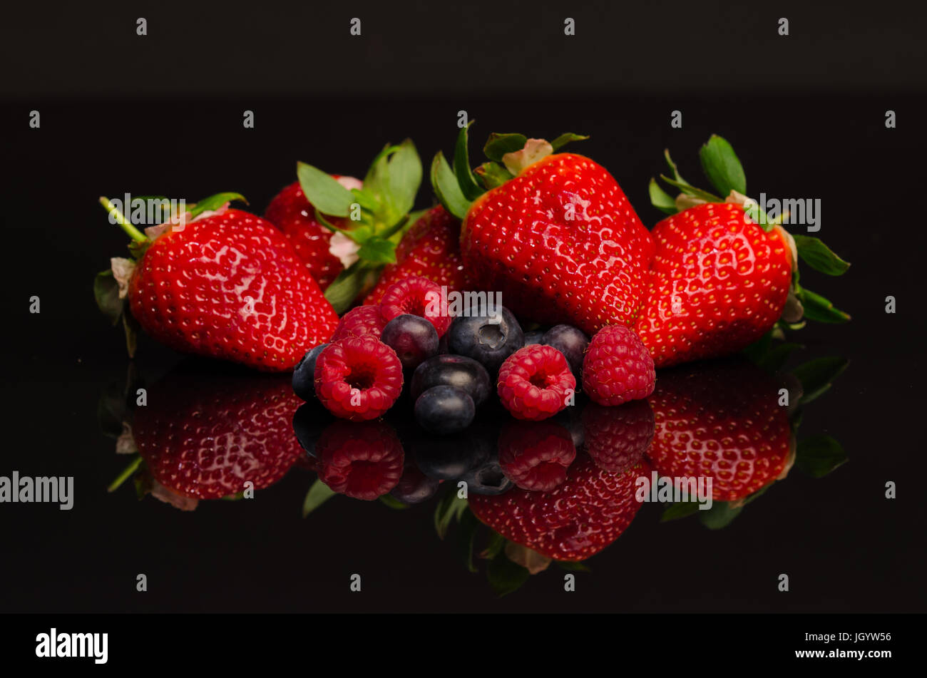 Erdbeeren, Himbeeren und Heidelbeeren auf schwarzen reflektierenden Hintergrund Stockfoto