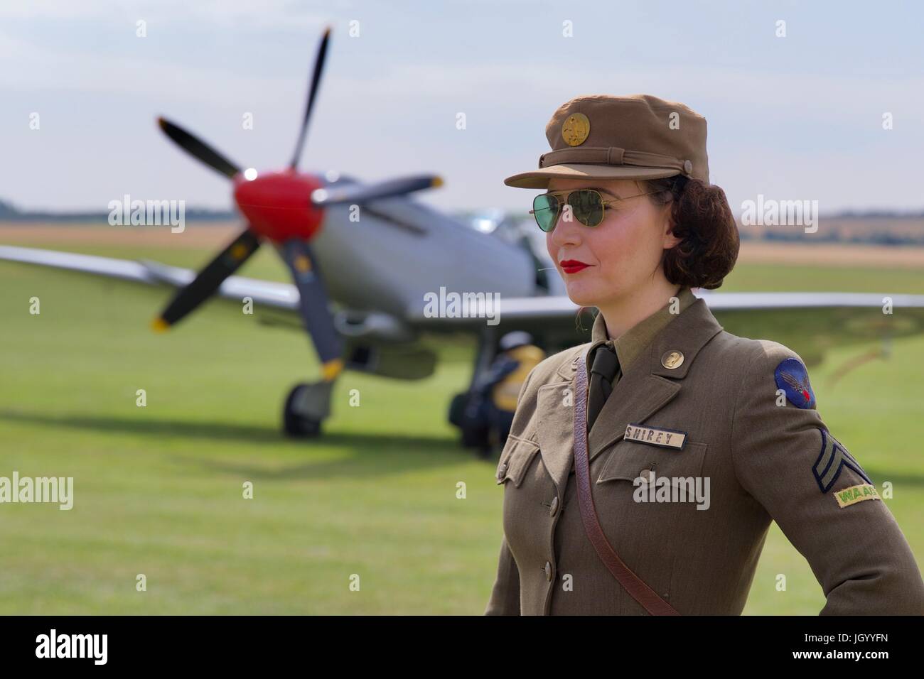 Eine junge Dame in Zeitraum einheitlich gekleidet mit einer Supermarine Spitfire Mk XVIII G-BUOS im Hintergrund bei den Flying Legends Air zeigen 2017 Stockfoto