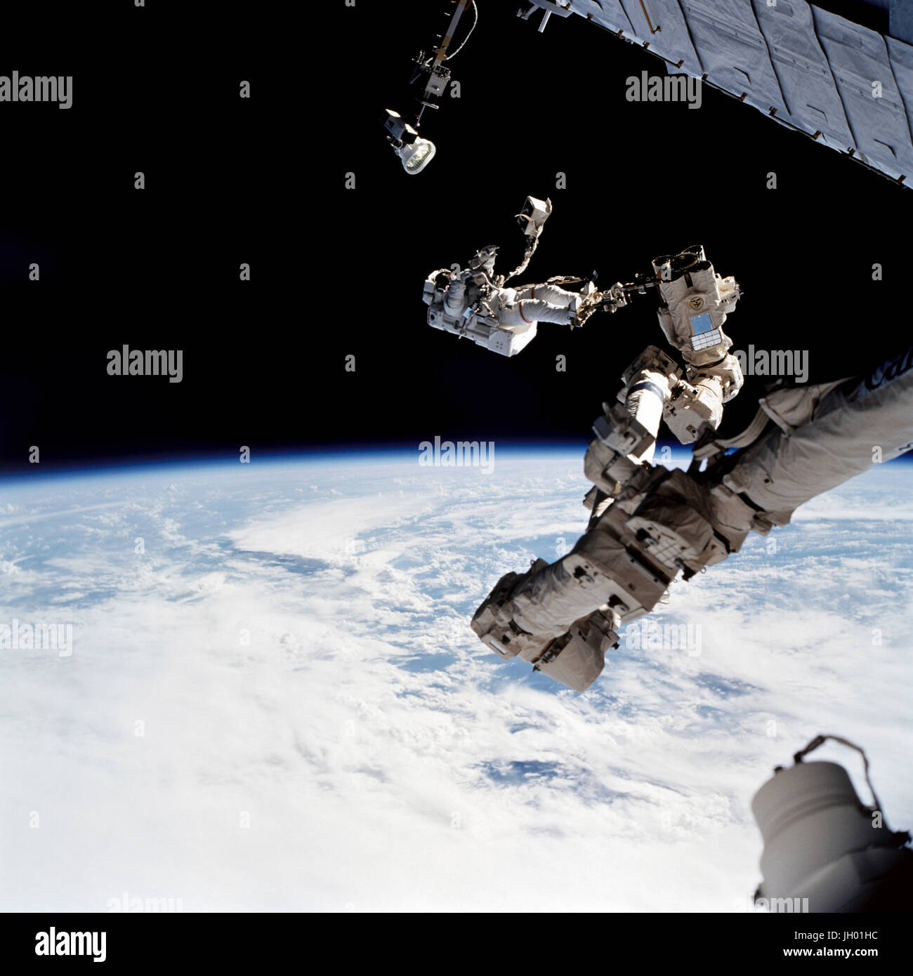 Astronaut David A. Wolf, STS-112 Missionsspezialist verankert an einem Fuß Fessel auf dem Space Station Remote Manipulator System (SSRMS) oder Canadarm2, trägt die Starboard One (S1) Außenborder Nadir externe Kamera. Die Kamera wurde während der Mission erste geplante Sitzung der Extravehicular Activity (EVA) am Ende der S1 Dachstuhl auf der internationalen Raumstation (ISS) installiert. Stockfoto