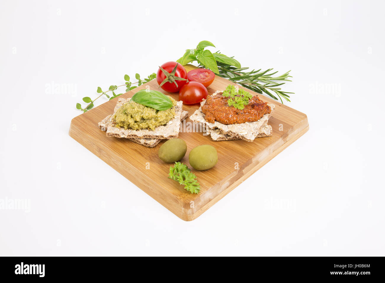 Eine köstliche Auswahl an Oliven, Paprika und Cherry Tomaten dips mit integraler Cracker: Snacks sind mit schönen frischen Kräutern dekoriert. Stockfoto