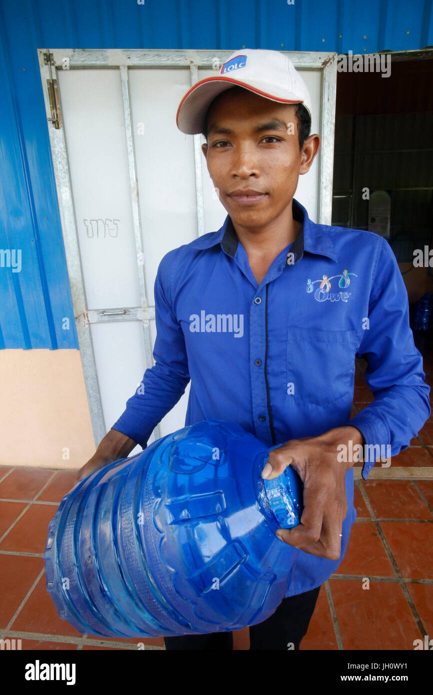 1001 Brunnen Wasser Unternehmen. Mitarbeiter tragen eine Korbflasche. Kambodscha. Stockfoto