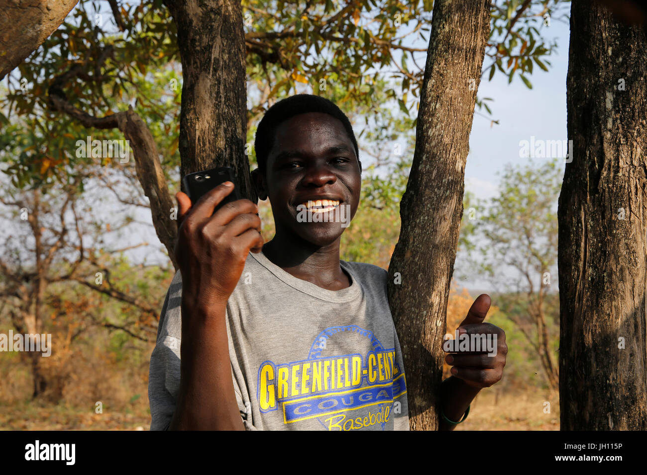 Ugandische hält ein Handy in einer abgelegenen ländlichen Gegend. Uganda. Stockfoto