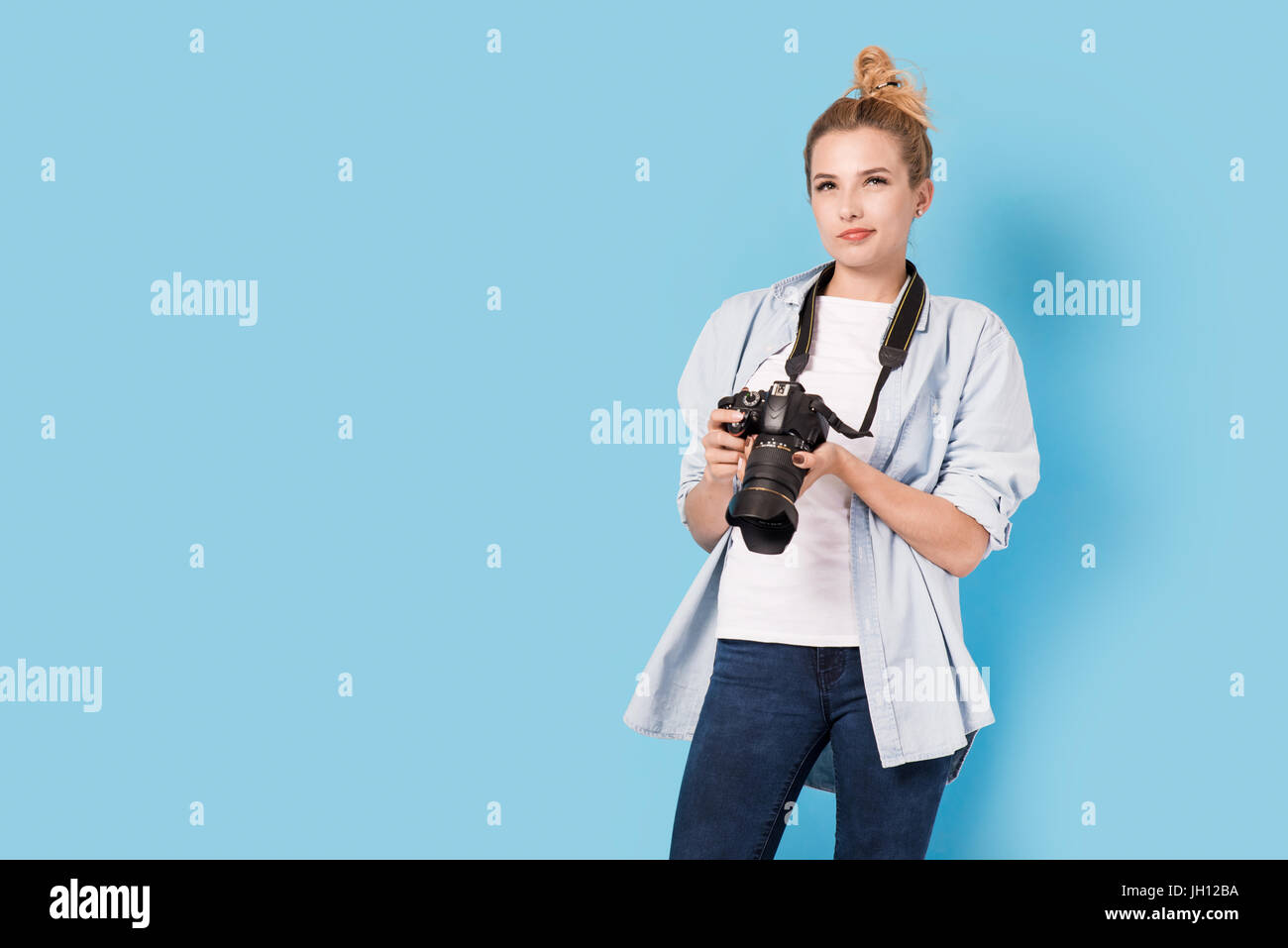 Frau-Fotograf fragt sich, wie nächsten Foto zu tun. Modell isoliert auf einem blauen Hintergrund mit Textfreiraum Stockfoto
