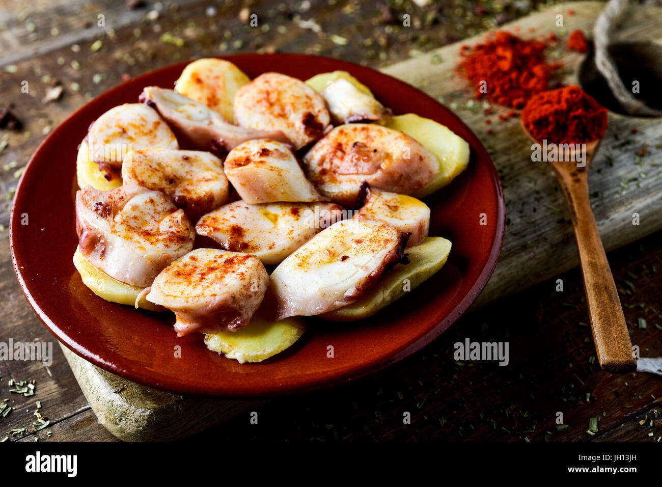 Nahaufnahme eines Steingut Platte mit Pulpo a la Gallega, eine Rezept von Octopus typisch in Spanien auf Kartoffeln serviert und gewürzt mit Paprika, auf einen rusti Stockfoto