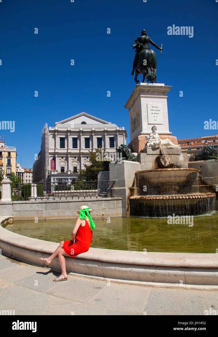 Frau in einem roten Kleid sitzt vor dem Teatro Real / Theatre Royal und das Denkmal für Felipe IV in Madrid Spanien Stockfoto
