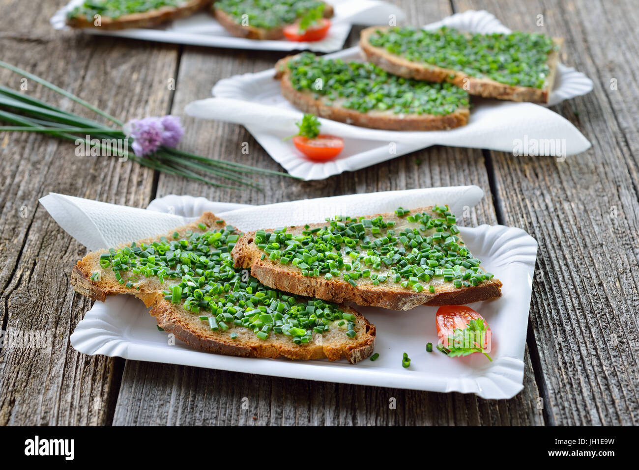 Suppen: Scheiben von frischem Bauernhaus Brot mit Butter und Schnittlauch auf weißem Papier Teller mit Servietten Stockfoto