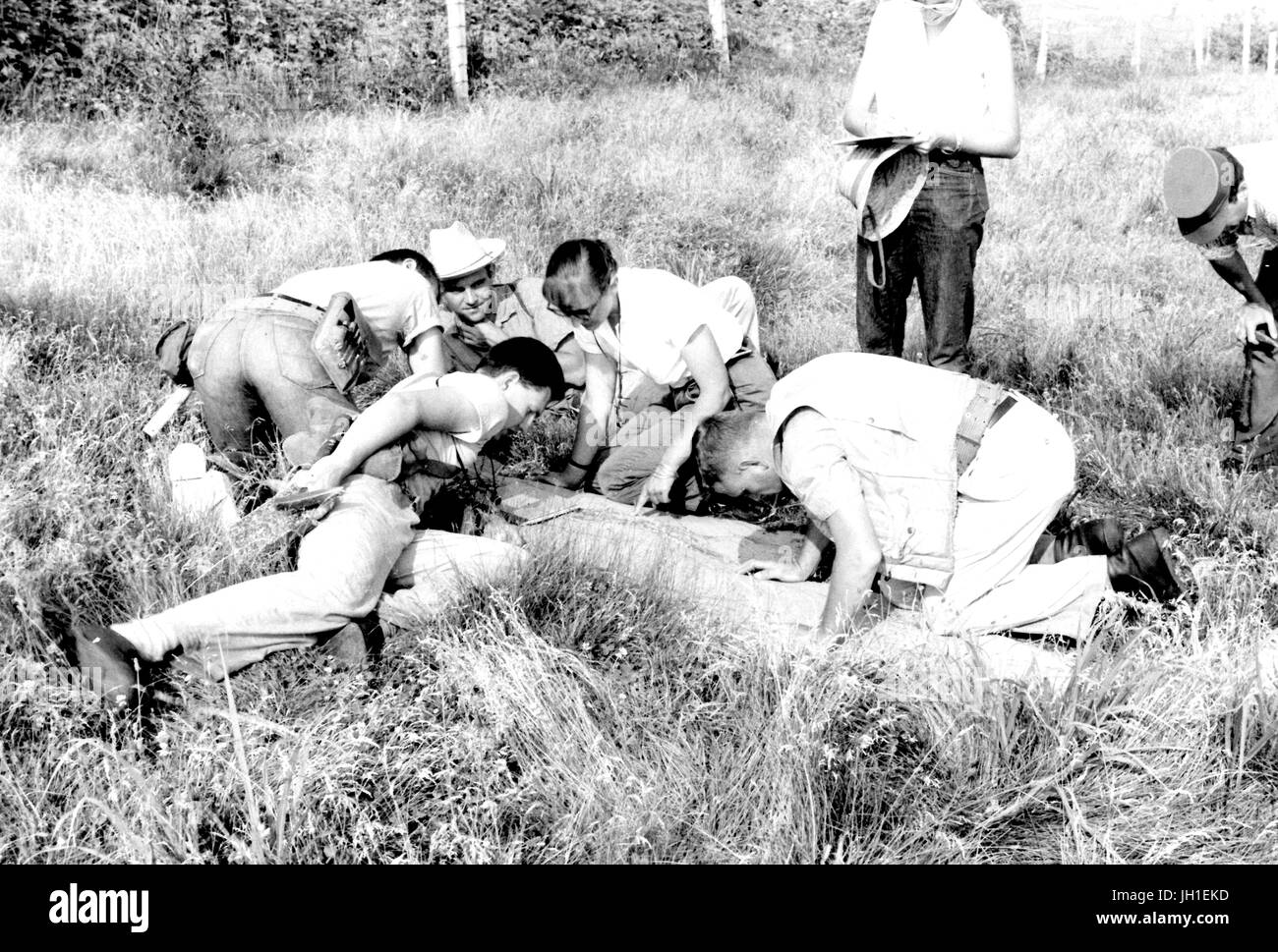 Geologie-Studenten der Johns-Hopkins-Universität kniete auf dem Feld Inhalt der Erde als ein Aufseher untersuchen sucht über die Studenten Schultern, Sommerwetter, 1921. Stockfoto