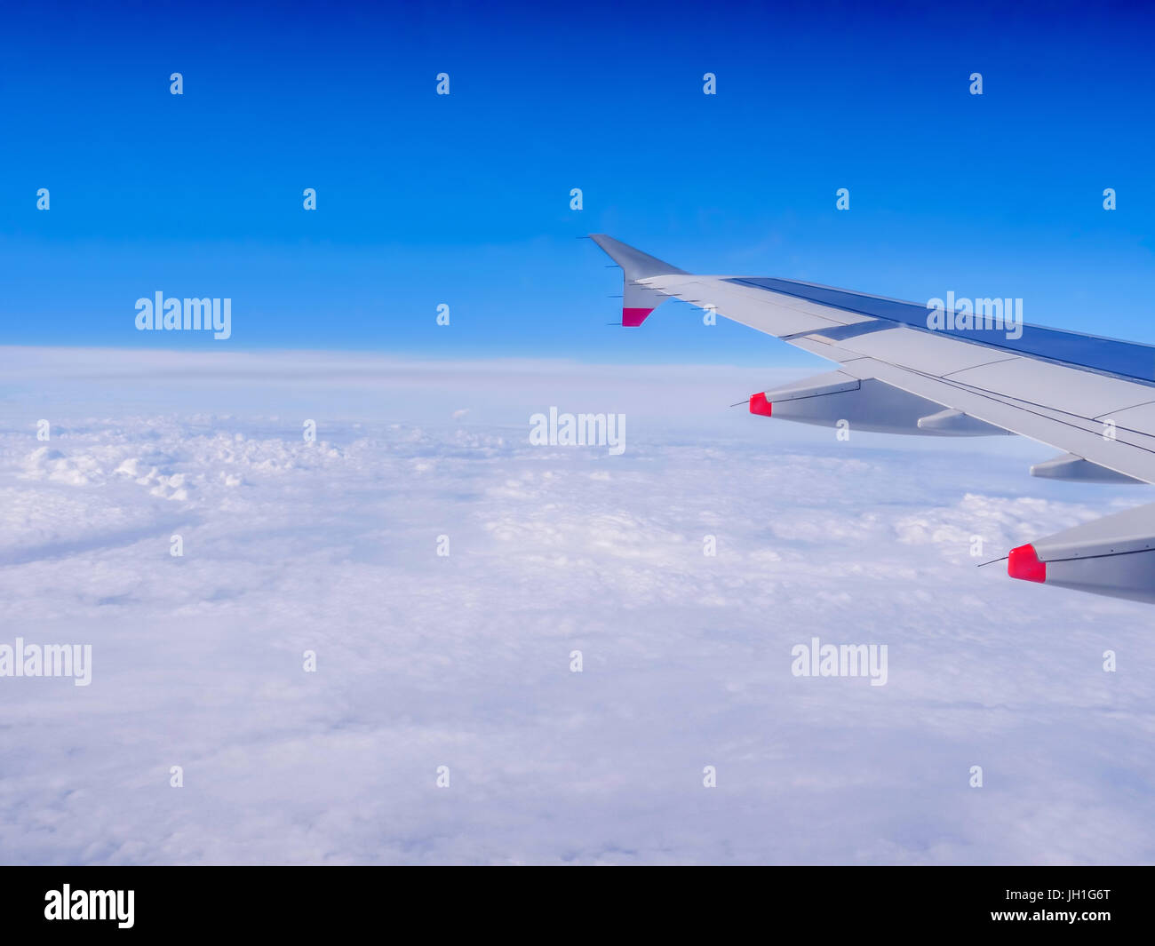 Blick aus dem Flugzeugfenster: eine Tragfläche über Wolken und blauer Himmel. Reisen mit dem Flugzeug. Flugzeug fliegen über der Erde auf 10000 m-50 ° C (-58,00 ° F). Stockfoto