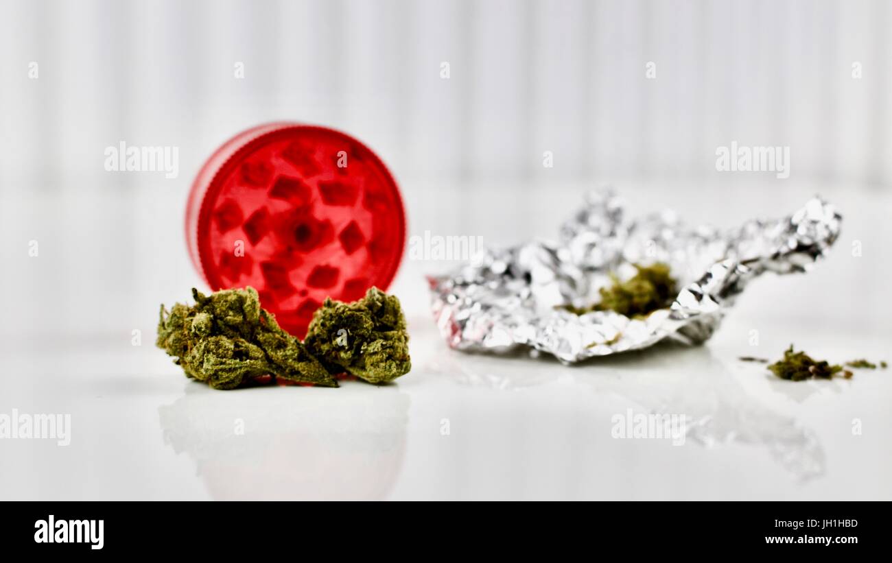 Trockenen grünen Marihuana auf dem Tisch, in der Nähe von rote Mühle und Unkraut Silber-Paket. Stockfoto