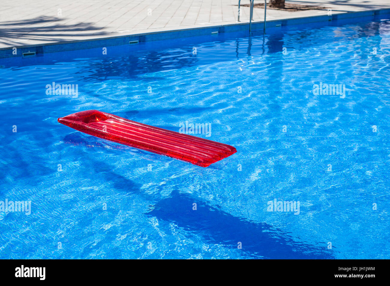 Rote aufblasbare Lilo liege schwebend in einem Schwimmbad Stockfoto