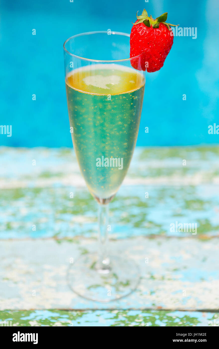 Glas Champagner mit Erdbeeren auf blauem Hintergrund Sommer-Pool-party Stockfoto