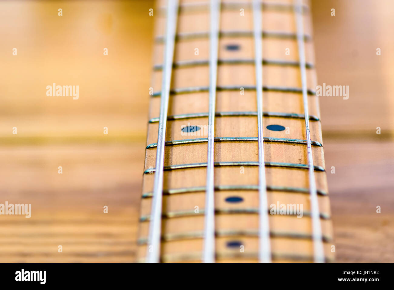 Nahaufnahme der elektrischen Bassgitarre Griffbrett, Tiefe des Feldes,  hölzernen Hintergrund unscharf gestellt Stockfotografie - Alamy