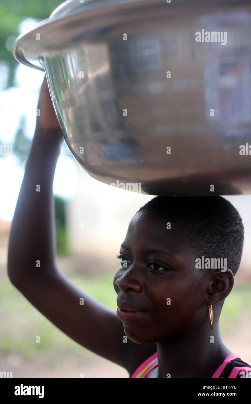 Afrikanisches Dorfleben. Afrikanische Mädchen tragen ein Becken auf Kopf. Togo. Stockfoto