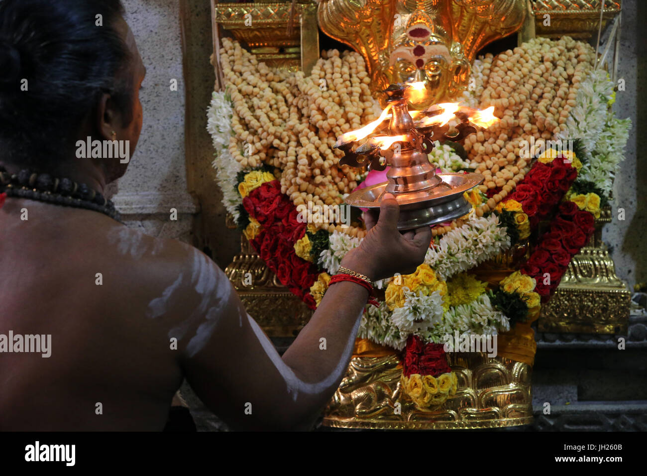 Sri Veeramakaliamman Hindu-Tempel.  Dakshinamurthy. Hinduistischen Brahmanen Priester mit einem Arthi (beleuchtete Kampfer) Morgen Puja-Zeremonie durchführen.  Singapur Stockfoto