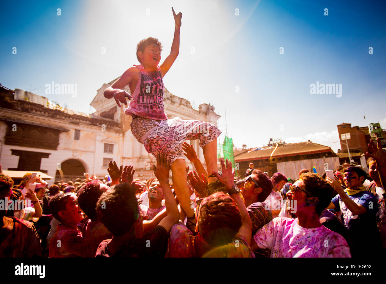 Junge, in die Luft geworfen, während des Festivals Holi Pigment wirft in Durbar Square, Kathmandu, Nepal, Asien Stockfoto