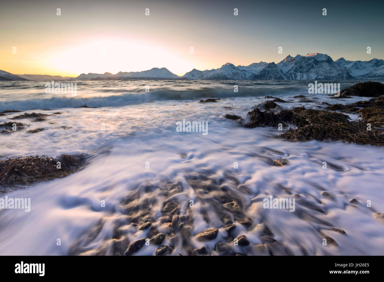 Das Abendlicht spiegelt sich auf den Wellen des kalten Meer stürzt auf den Felsen, Djupvik, Lyngen Alpen, Troms, Norwegen, Skandinavien Stockfoto