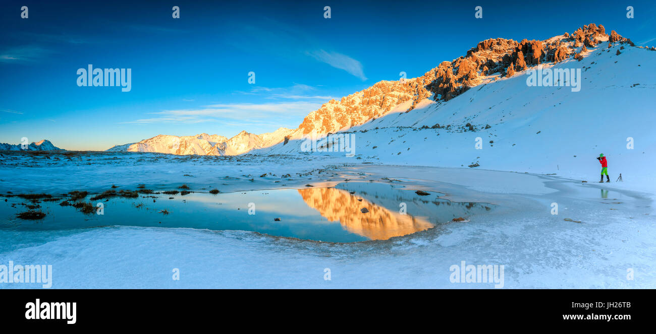 Panorama des Sees, Piz Umbrail im Morgengrauen mit dem Fotografen in Aktion, umrahmt von Schnee, Braulio Tal, Valtellina, Lombardei, Italien Stockfoto