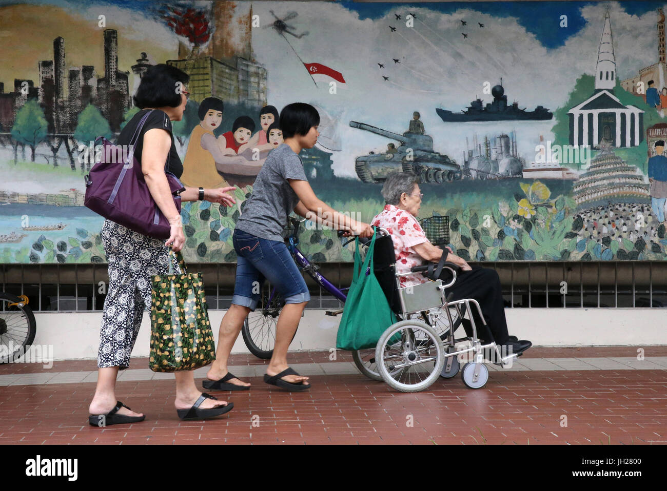 Frau, ältere Frau im Rollstuhl zu schieben.  Singapur. Stockfoto